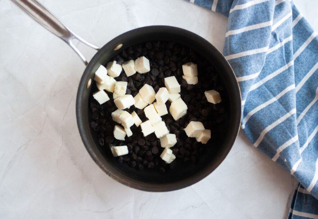 Chocolate chips and cubed butter sitting in a saucepan before melting.