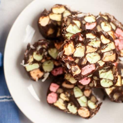 A close-up view of sliced church window cookies on a white plate, showing colorful pastel marshmallows embedded in a glossy chocolate mixture.