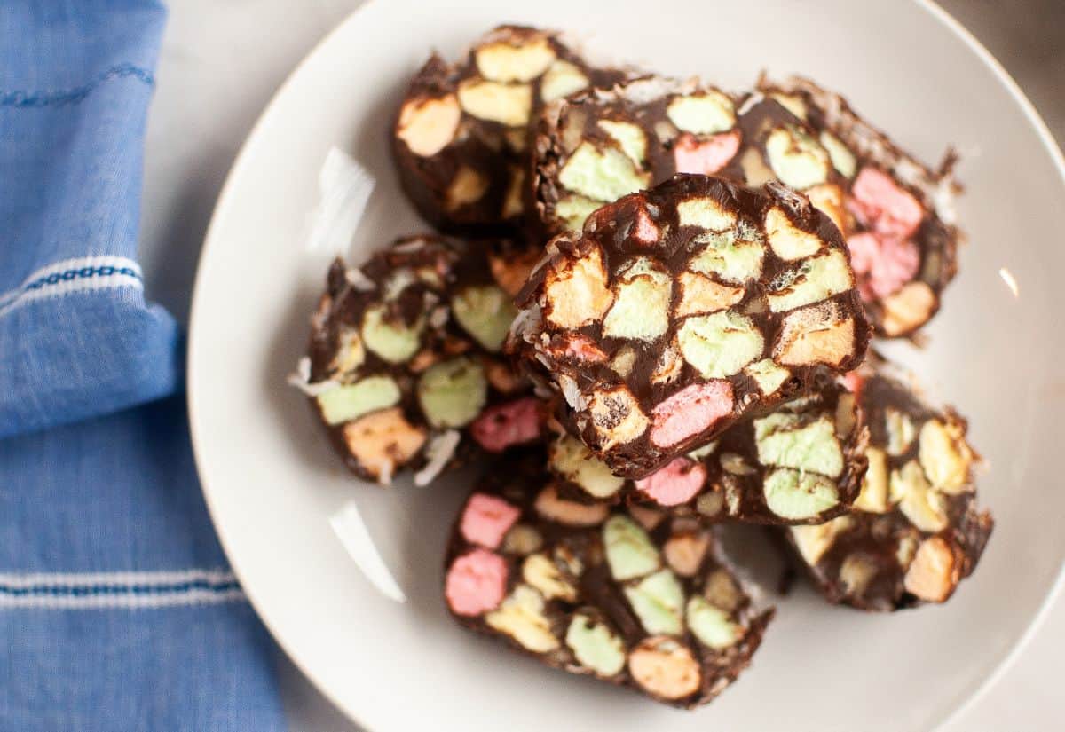 A close-up view of sliced church window cookies on a white plate, showing colorful pastel marshmallows embedded in a glossy chocolate mixture.