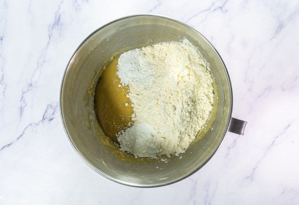 Dry ingredients piled on top of the wet cookie mixture in a mixing bowl.