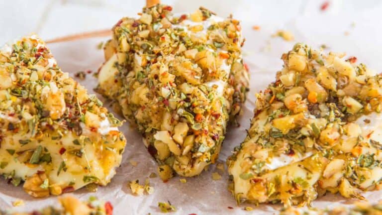 Christmas tree-shaped cheese ball on a platter, decorated with fresh herbs.