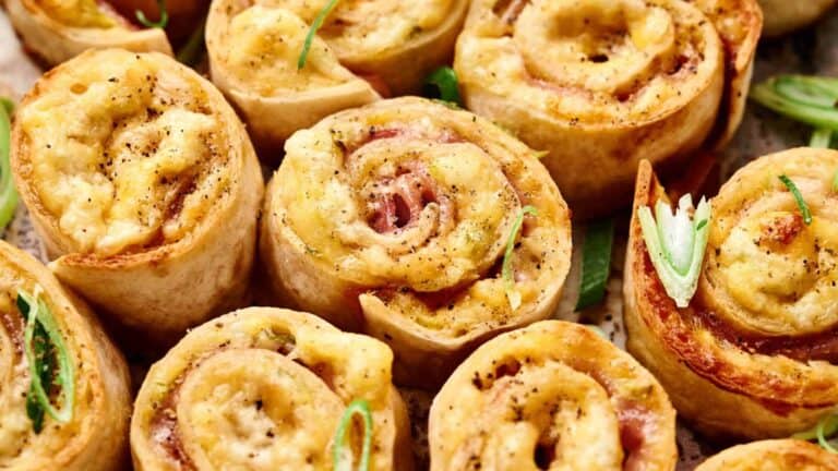 A close-up of rolled-up ham and cheese pinwheels with a golden-brown crust.