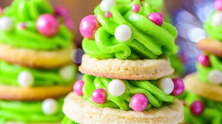 Christmas tree-shaped cookies stacked and decorated with colorful icing and festive toppings.