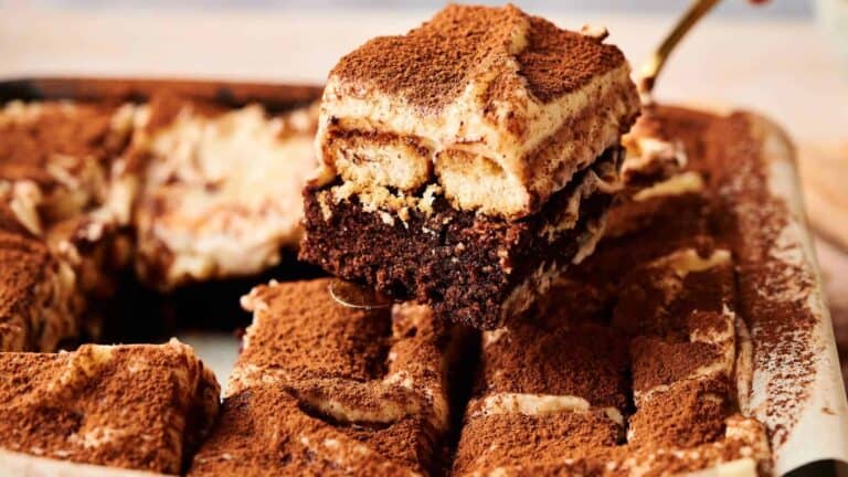 Tiramisu brownies with a layer of soft cream and cocoa powder topping.