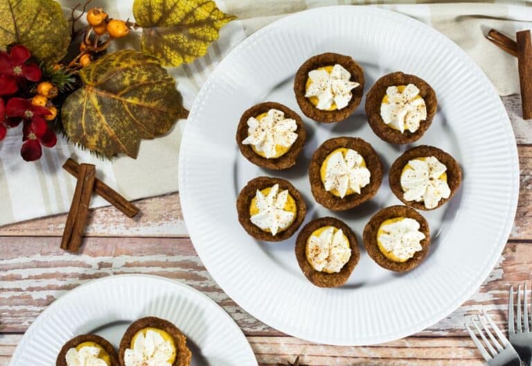 Pumpkin Cannoli Cookie Cups on a plate with a fall-themed background, topped with whipped cream and sprinkled with cinnamon.