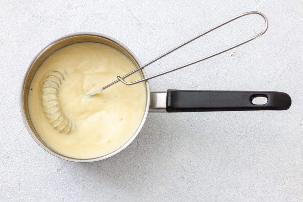 A saucepan with a smooth, creamy mixture being whisked, ready to add to the vegetable chowder.