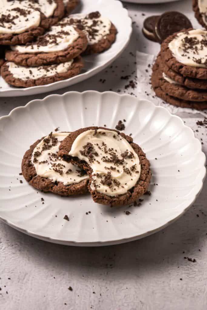 A close-up of a frosted Oreo cookie with a bite taken out, showing the soft chocolate cookie base and creamy frosting.