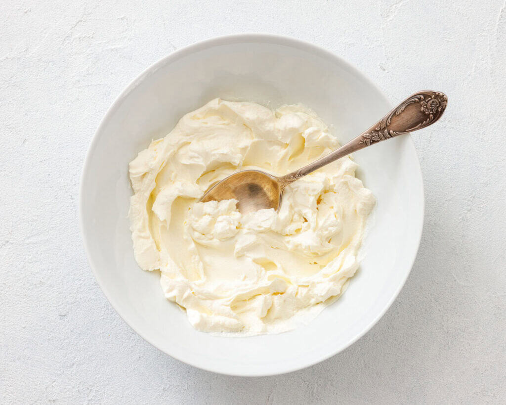 A white bowl with softened cream cheese, ready to be mixed with other ingredients for the cranberry dip.