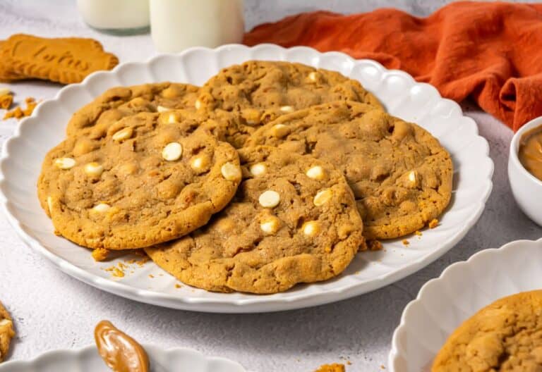 A close-up view of Crumbl Biscoff Cookies on a white plate, with visible white chocolate chips and a soft texture.