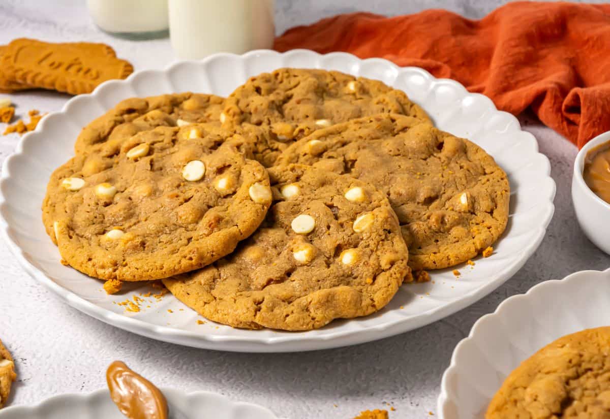 A close-up view of Crumbl Biscoff Cookies on a white plate, with visible white chocolate chips and a soft texture.