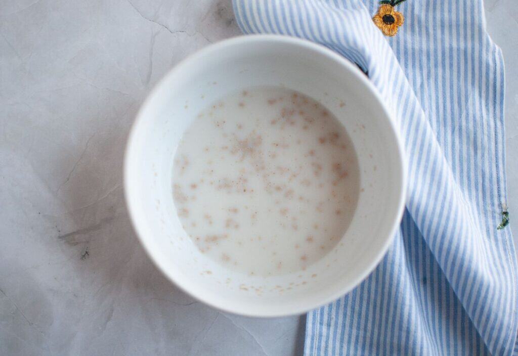 A bowl of yeast dissolved in warm milk and water, ready to be set aside for the recipe.