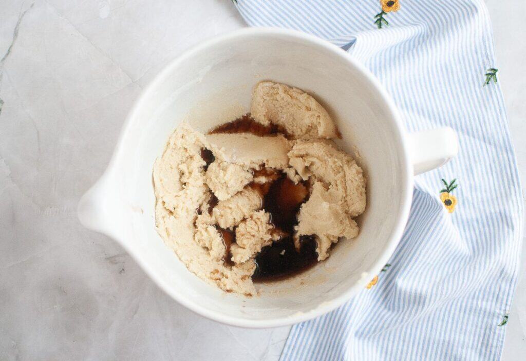 A bowl of dough with corn syrup and vanilla extract added, in preparation for mixing.