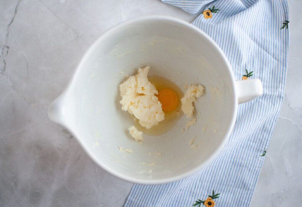 A bowl with creamed butter, sugar, and egg mixture in the stand mixer.