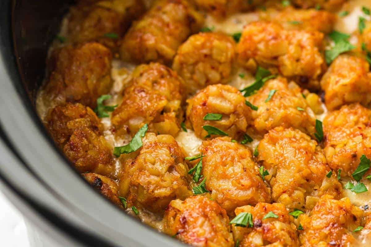 Close-up of Slow Cooker Cowboy Casserole garnished with chopped parsley, inside a slow cooker.