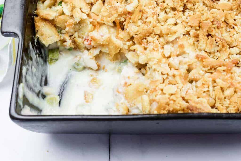 A close-up of a Cheesy Ritz Cracker Chicken Casserole dish with a portion missing from one side.