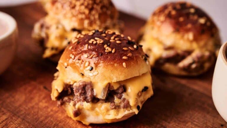 Mini hamburger sliders with cheese and meat patties on sesame seed buns.
