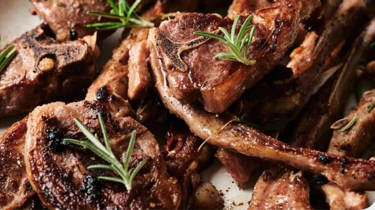 Grilled lamb chops with a caramelized crust, garnished with rosemary and freshly ground pepper.