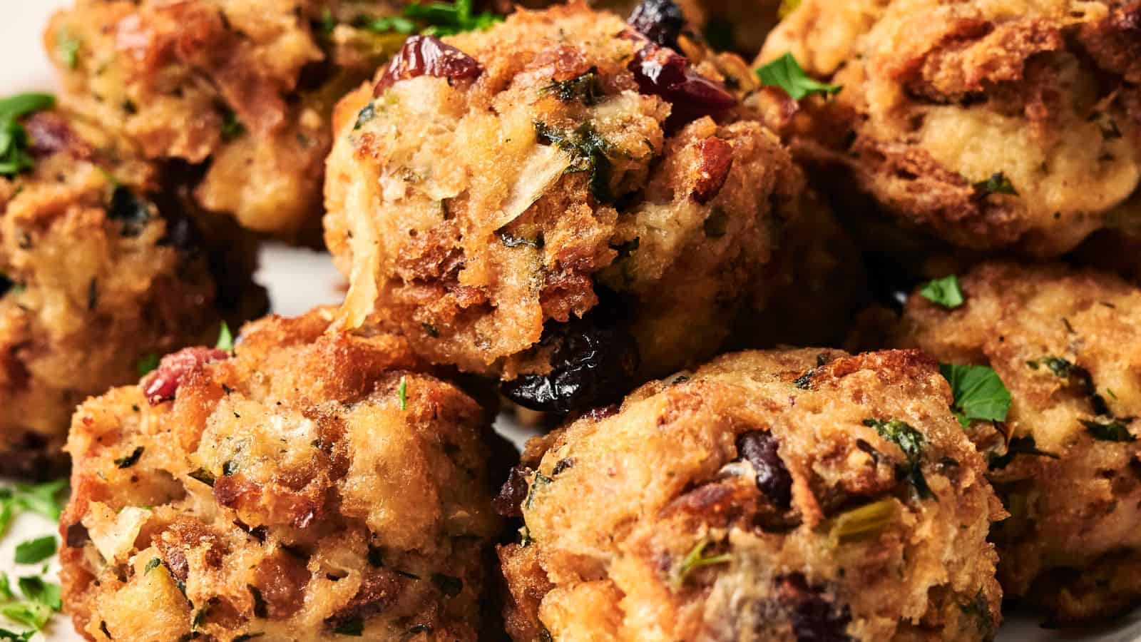 Close-up of several stuffing balls containing herbs and dried cranberries, garnished with fresh parsley.