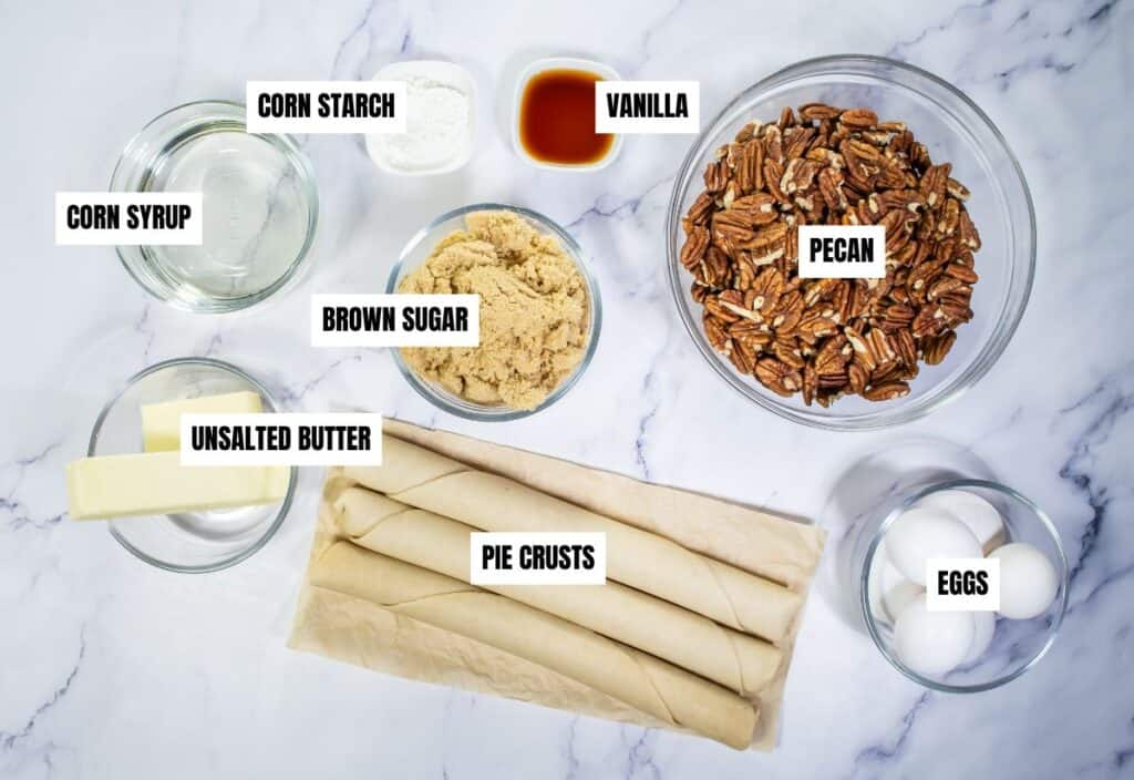 Ingredients for the pecan pie, including corn syrup, brown sugar, butter, pie crusts, eggs, and pecans, arranged on a countertop.