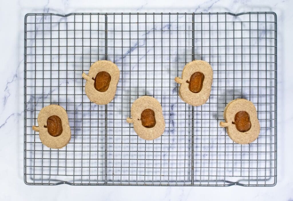 Pumpkin cookies with pumpkin butter filling placed on a wire rack, ready for assembly.