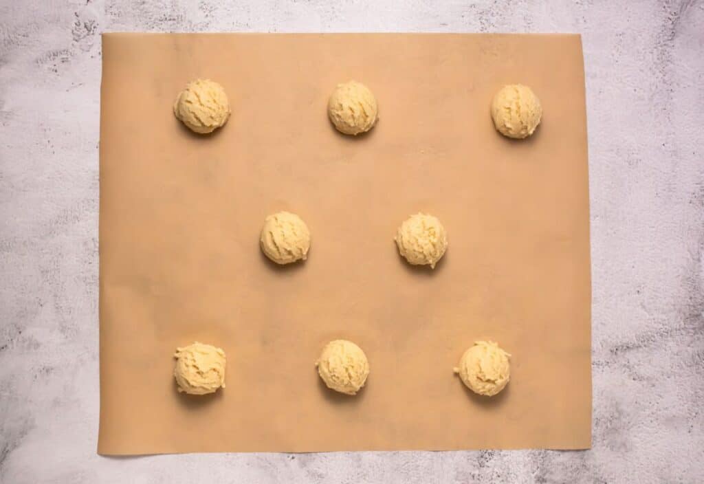 Cookie dough balls placed on parchment paper for baking.