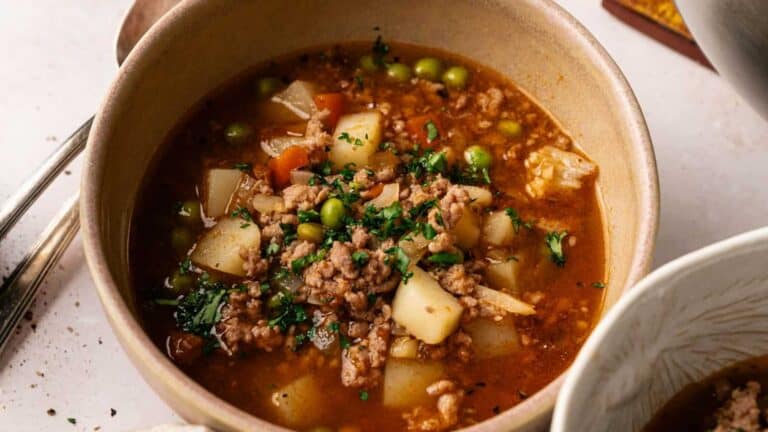 A bowl of hamburger soup with ground beef, vegetables, and a savory broth.