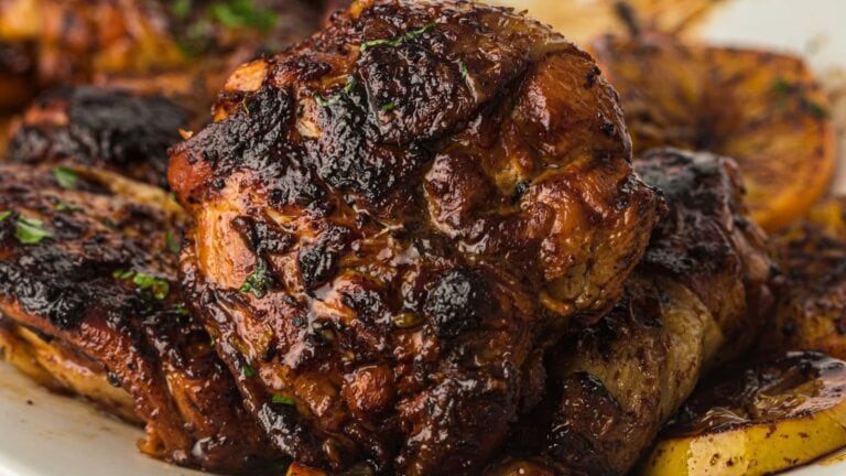 A skillet-cooked chicken thigh glazed with miso butter and burnt honey, garnished with green herbs.