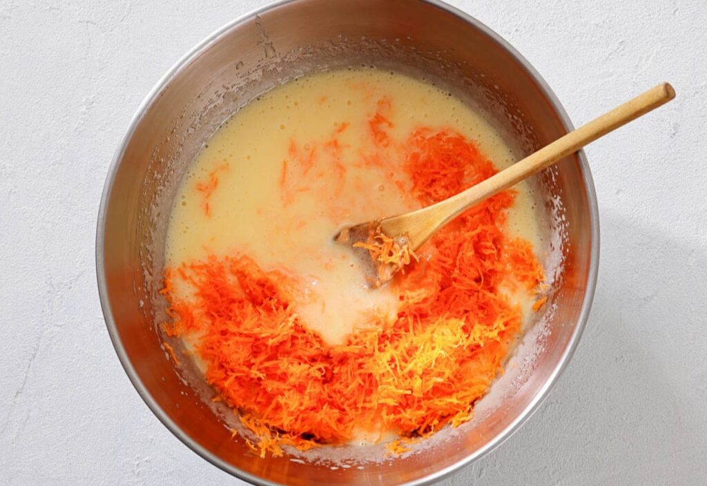 Large bowl of batter with shredded carrots stirred in.