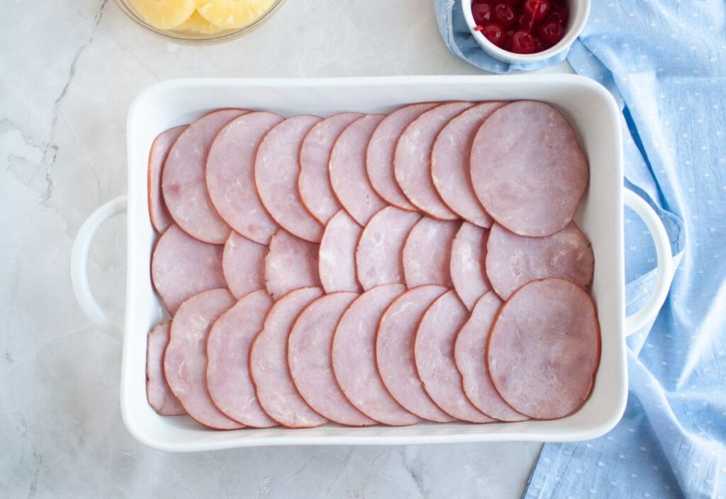 Baking dish layered with ham slices.