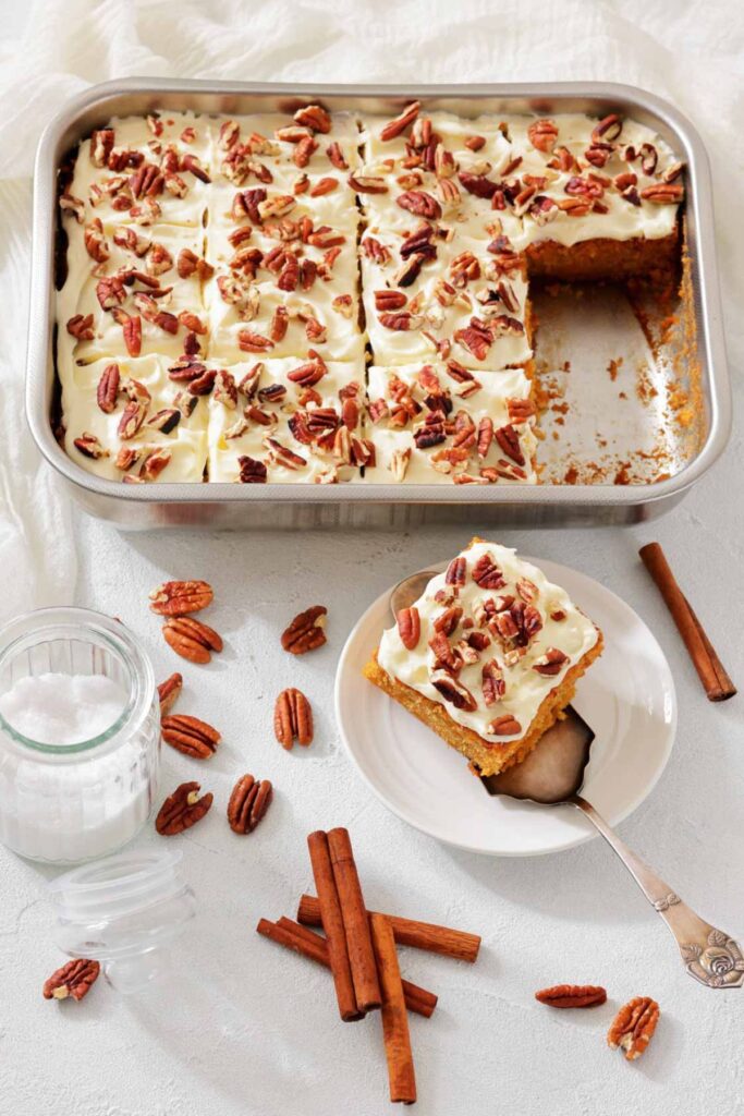 Frosted cake with pecans in a pan, one piece served on a plate.